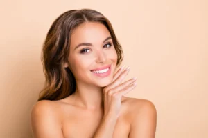 Close-up of a woman touching her glowing face in Wakefield, MA | Infinite Beauty Med Spa