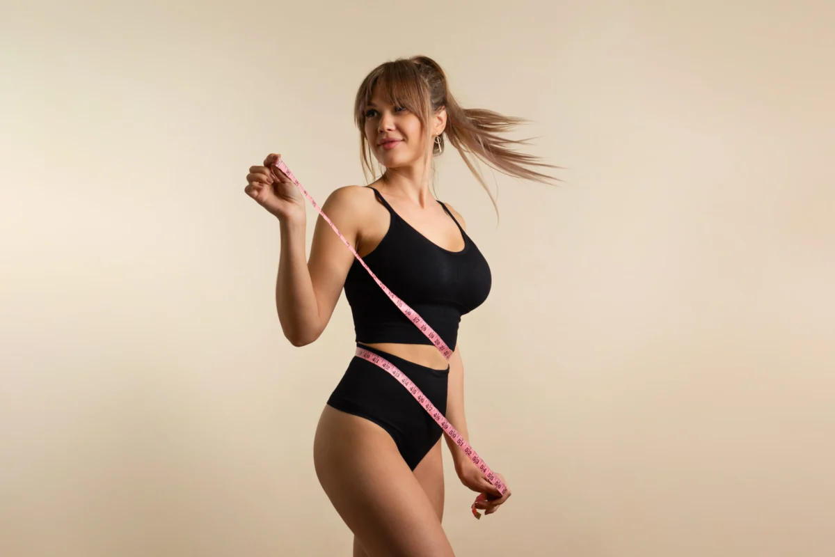 Slim healthy girl in black underwear with measuring tape at waist in Wakefield, MA | Infinite Beauty Med Spa
